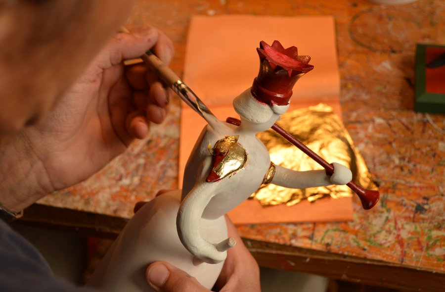 Nahaufname der Hand eines Künstlers, der auf den Schultern einer Engelsfigur mit einem Pinsel Blattgold auflegt